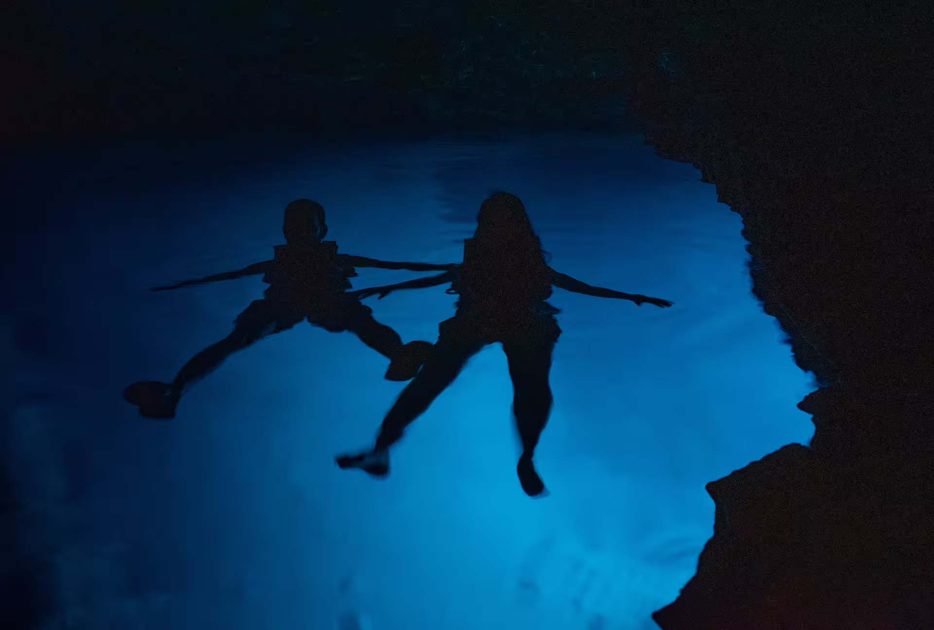 Kayakers floating in a glowing blue sea cave on the Kardamyli and Stoupa sea kayak tour in Mani, Greece