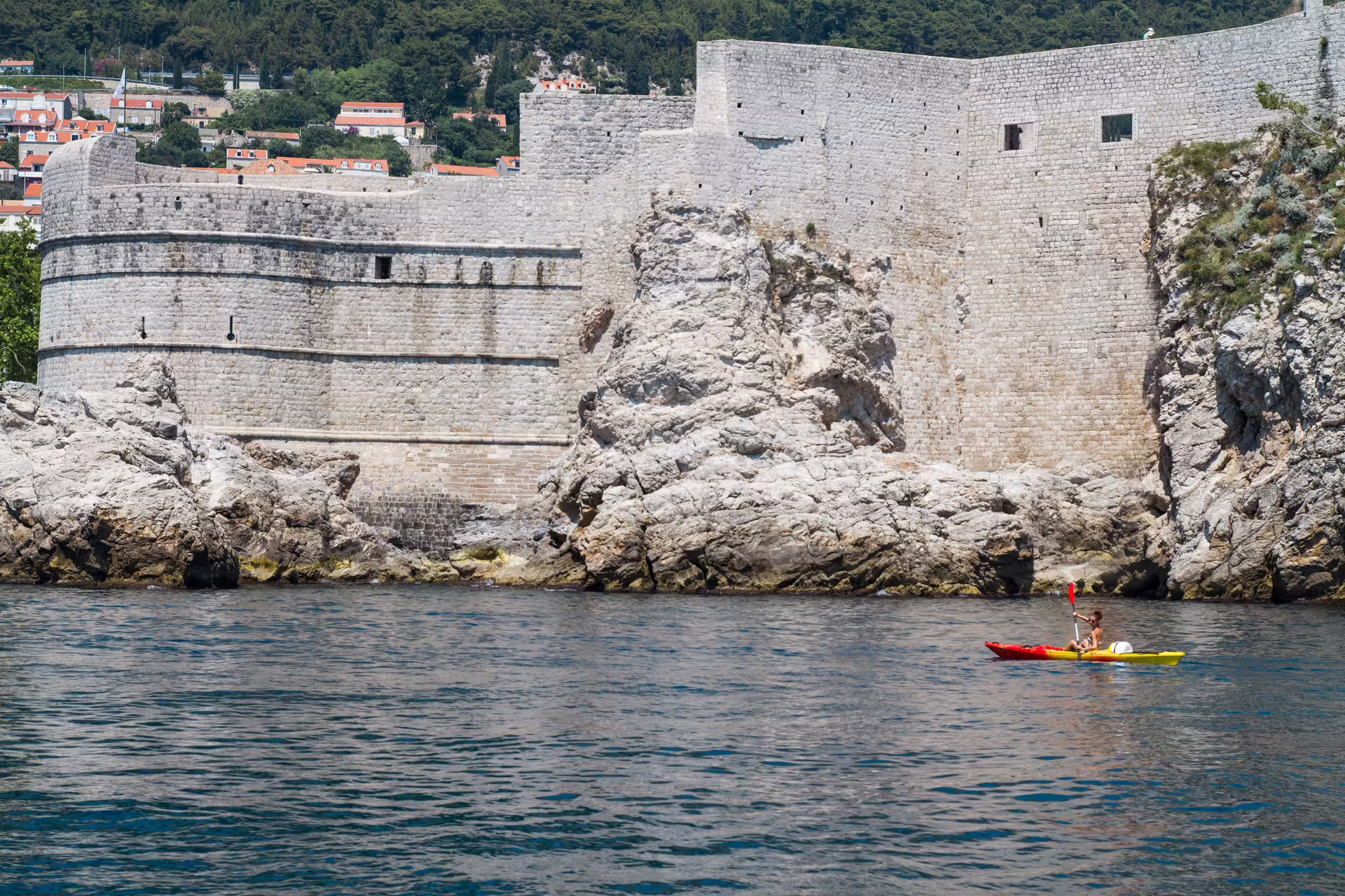 Sea kayak paddling past Dubrovnik city walls on sunset kayaking and snorkeling tour, with water and wine included