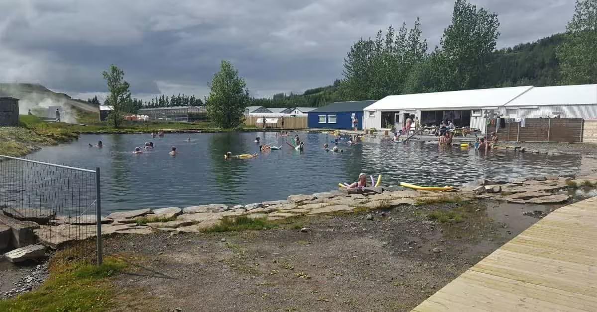 Swimmers enjoying the Secret Lagoon geothermal hot spring pool in Iceland on a cloudy day
