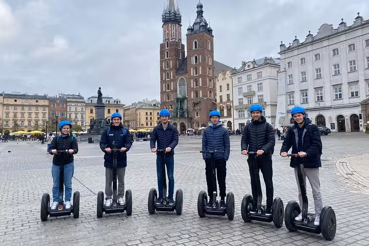 Tourists on Segways exploring Krakow's Main Market Square, with St. Mary's Basilica in the background.