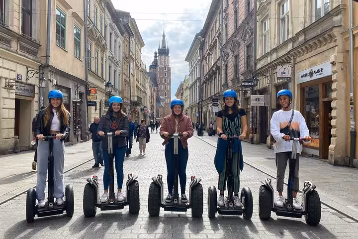 Group of tourists on a Segway tour in Krakow's picturesque old town, showcasing vibrant architecture and cobbled streets.