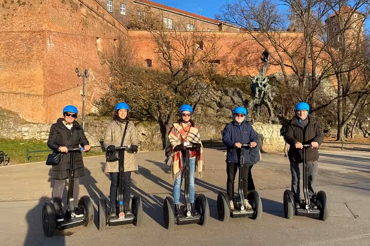 Group of people enjoying a Segway tour in Krakow, posing in front of the historic Wawel Castle.