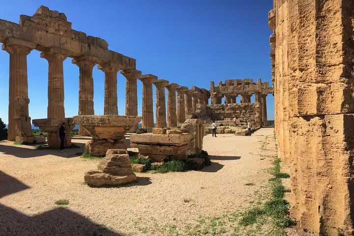 Visitors exploring well-preserved Doric columns and inner sanctuary of Selinunte Archaeological Park on a guided tour from Palermo