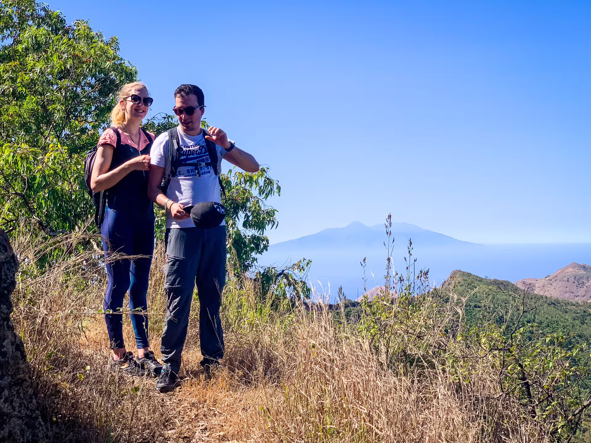 Two hikers enjoying panoramic views at Serra Malagueta Natural Park under a clear blue sky.