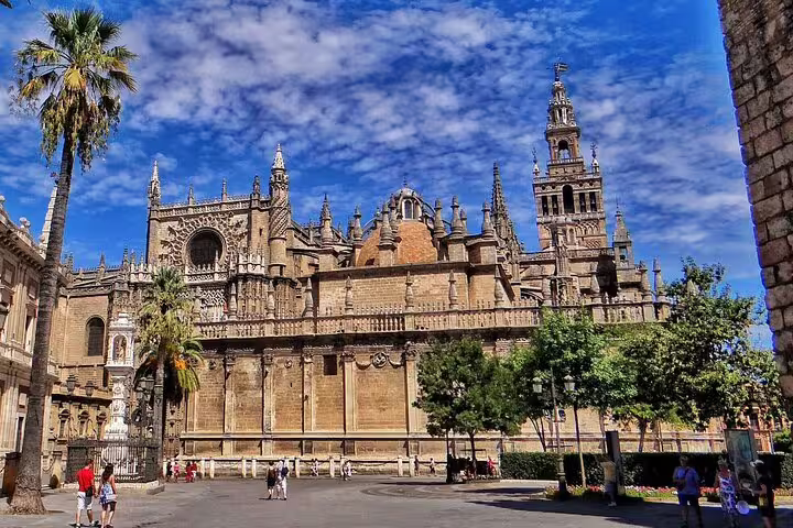 Gothic architecture of Seville Cathedral under a vibrant sky, a highlight of the Lisbon to Seville private journey.