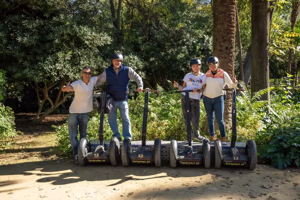 Group enjoying a Seville historical Segway tour surrounded by lush greenery on a sunny day.