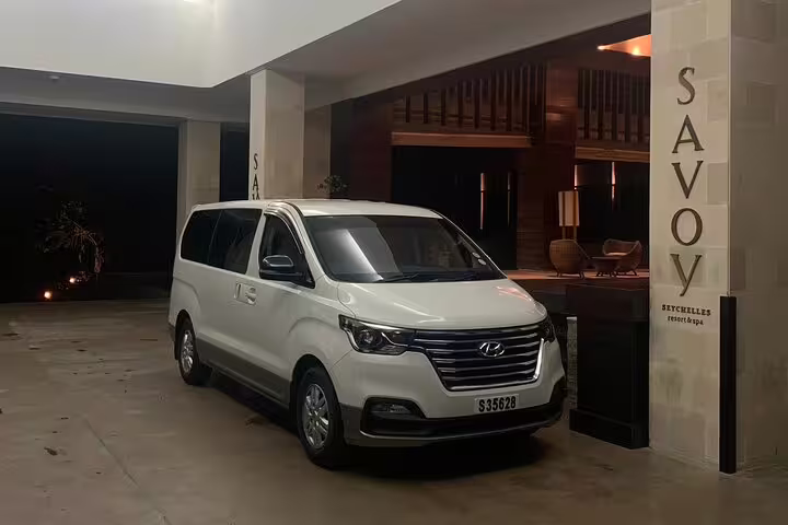 White transfer van parked outside Savoy Seychelles Resort, ideal for convenient one-way hotel transfers.