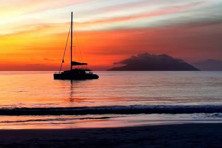 Sailboat silhouetted against a vibrant Seychelles sunset, ideal backdrop for serene airport and hotel transfers.