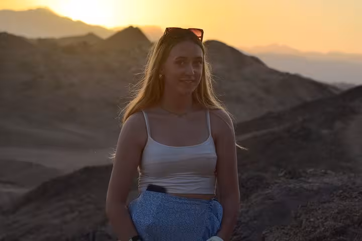 Traveler at sunset in Sharm El-Sheikh desert mountains, evening ATV safari with camel ride, BBQ dinner and show