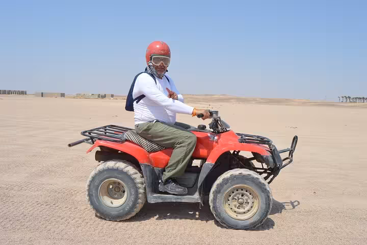 Guest riding red ATV quad across Sharm El-Sheikh sand dunes, desert safari with stargazing and BBQ dinner