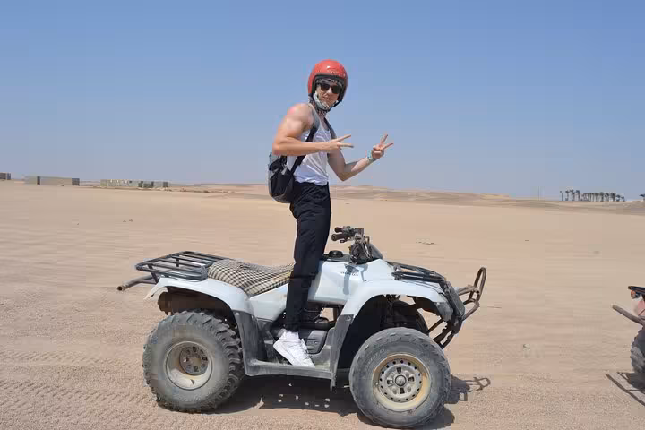 Traveler posing on quad bike in Sharm El Sheikh desert, ATV ride experience with stargazing and BBQ dinner
