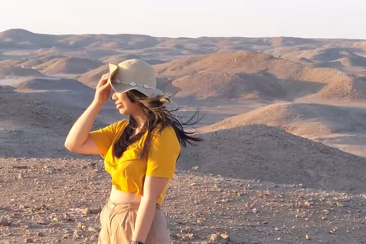 Traveler in hat overlooking Sharm El-Sheikh desert mountains at sunset on ATV quad adventure and stargazing tour