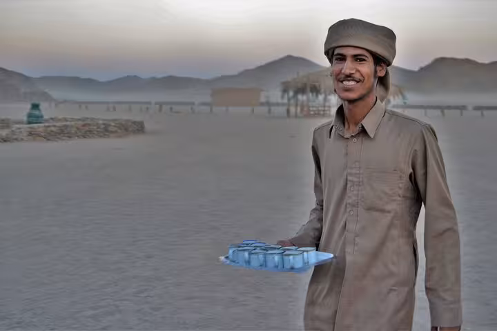 Bedouin host serving tea during Sharm El-Sheikh desert tour with ATV ride, camel trek, BBQ dinner and show