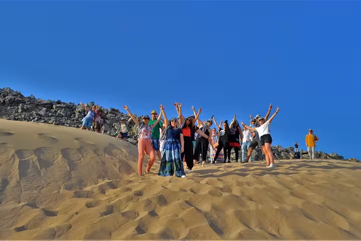 Tour group cheering on golden sand dunes in Sharm El-Sheikh after an adrenaline desert buggy safari experience