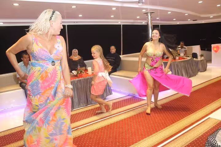 Belly dance show with guests dancing on Sharm El Sheikh evening oriental dinner cruise boat deck