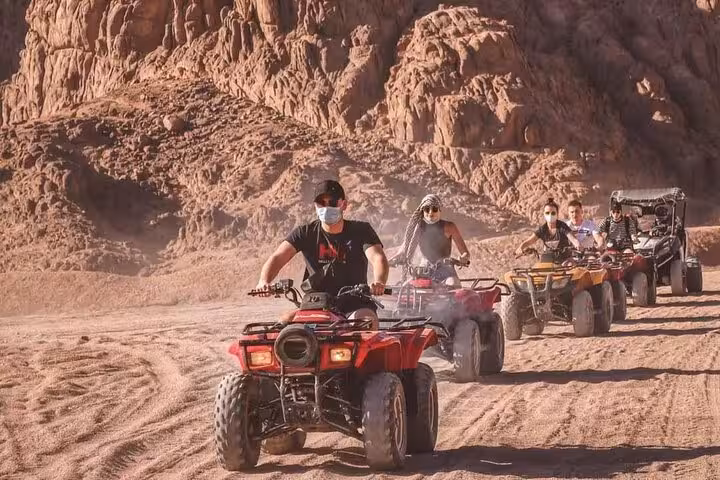 Group quad biking through rocky Sinai canyon on Sharm El Sheikh Bike Camel Canyon Tour desert ride