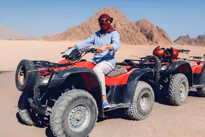 Rider on red ATV quad in Sharm El-Sheikh desert with mountains, part of stargazing and BBQ dinner tour