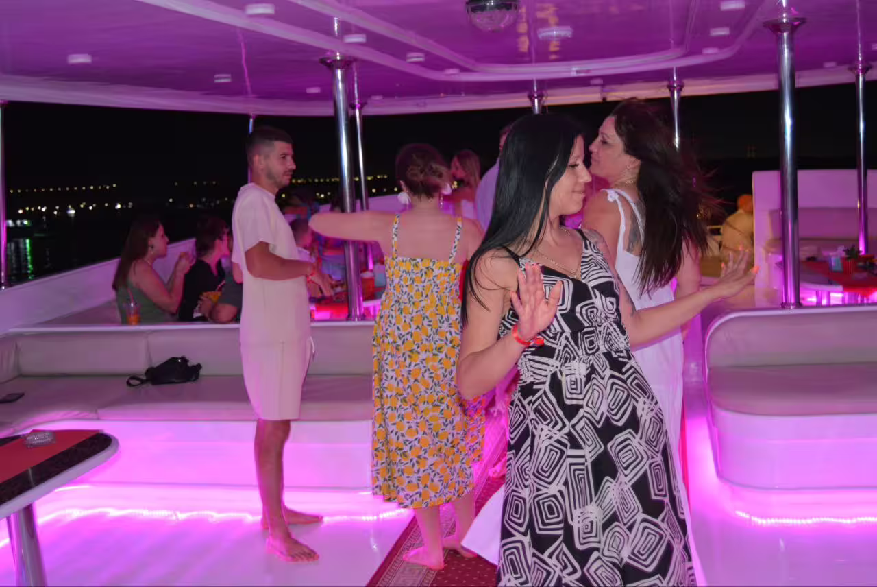 Party atmosphere on Sharm El Sheikh VIP dinner cruise boat with dancing guests and neon lighting on deck