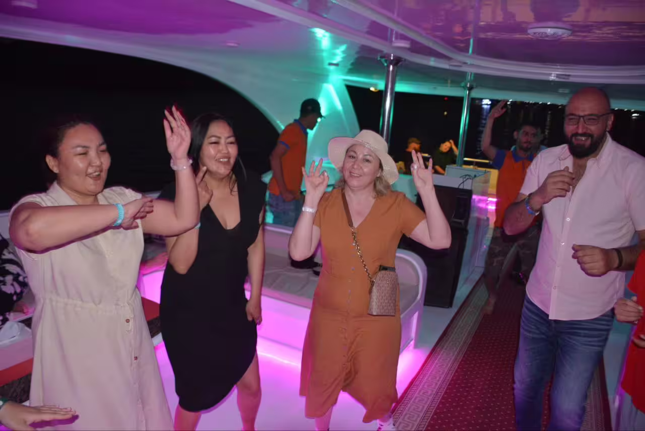 Friends enjoying onboard party on Sharm El Sheikh VIP dinner cruise boat with music, lights, and sea breeze