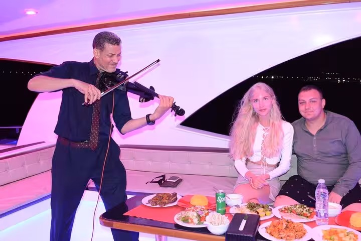Live violinist serenades couple during Sharm El Sheikh oriental dinner cruise with evening entertainment