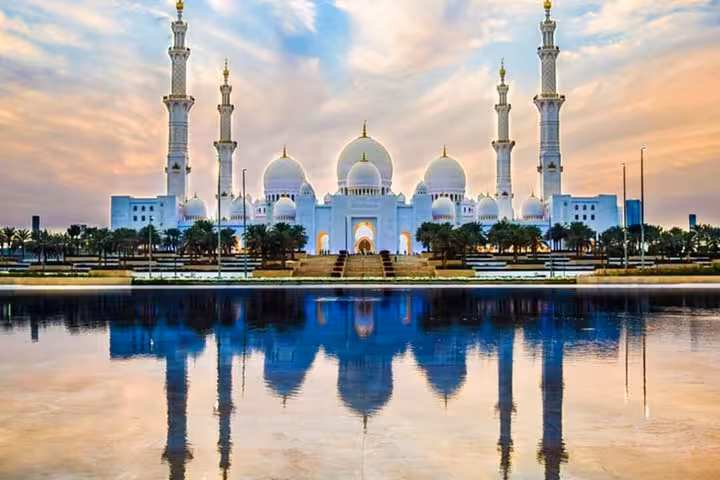 Marvel at the stunning reflection of Sheikh Zayed Grand Mosque at sunset during the Abu Dhabi City Tour.
