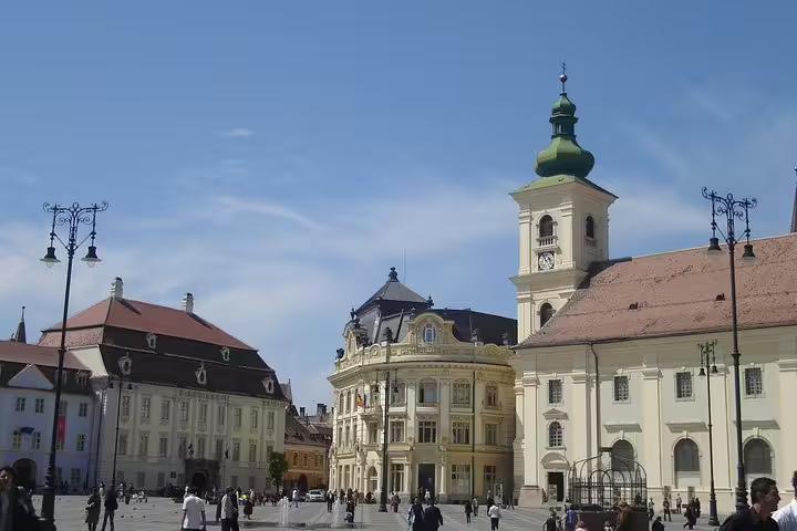 Historic main square in Sibiu, Transylvania, with baroque buildings and church tower under blue sky