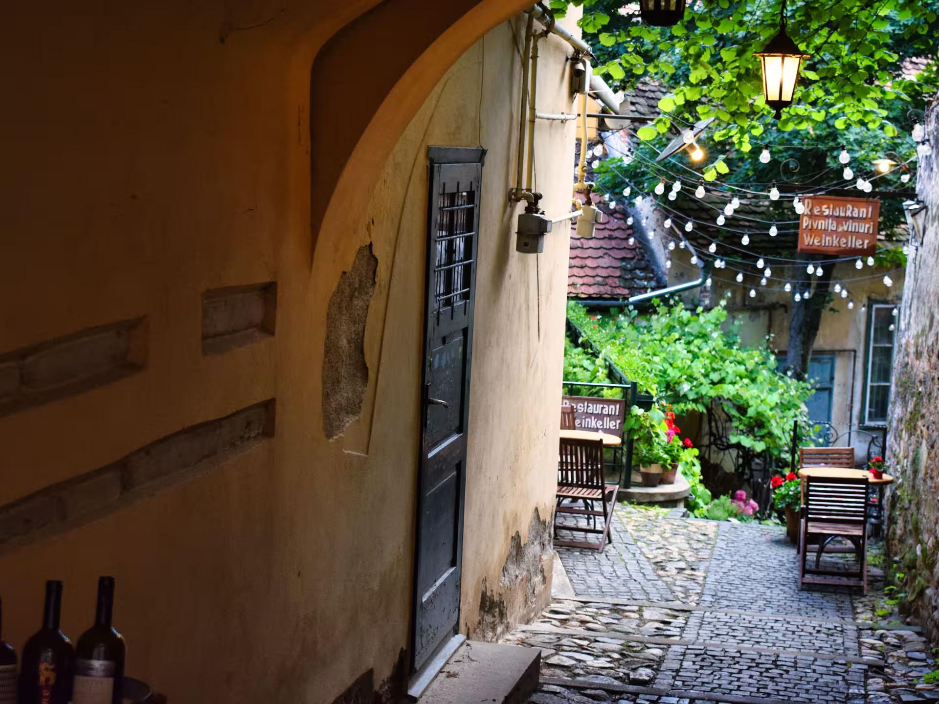 Charming cobblestone courtyard of a Sibiu wine cellar restaurant with string lights on a Cluj-Napoca day trip
