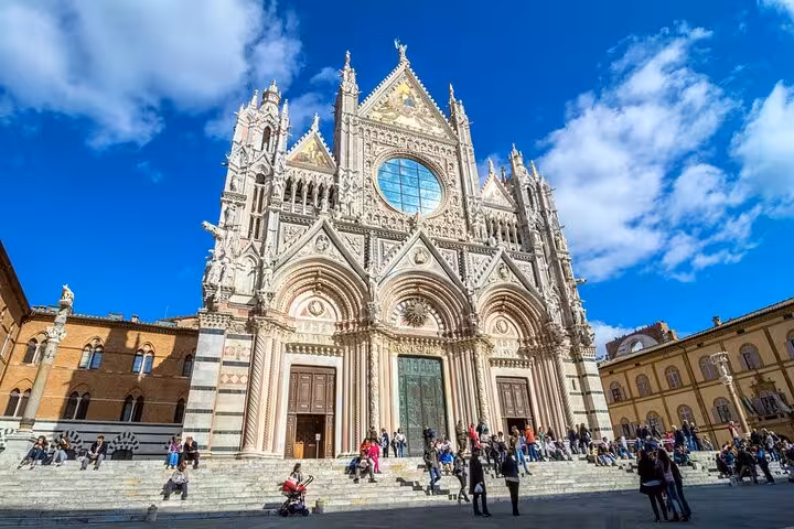 Explore the stunning facade of Siena Cathedral under a vibrant blue sky during your private Chianti wine tour.