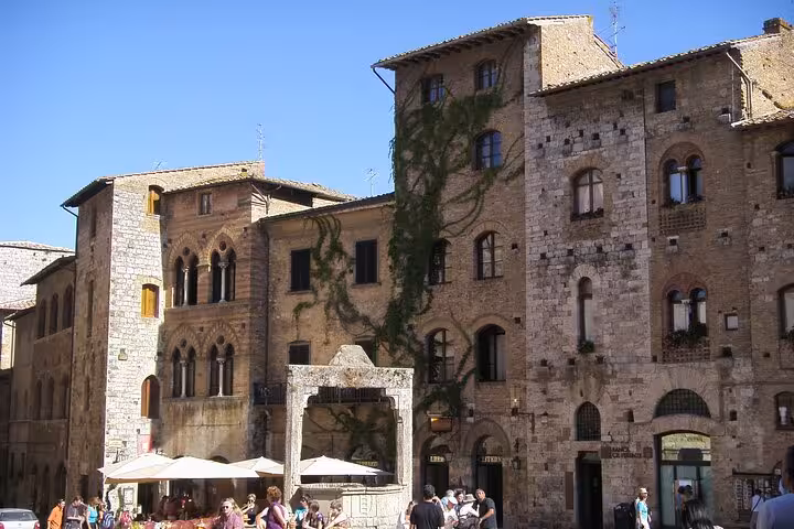 Charming medieval architecture in Siena's historic square, featuring rustic stone buildings and bustling cafes.