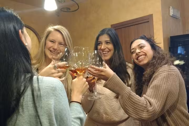 Group of friends enjoying a wine tasting experience in a cozy Tuscan setting, part of a small group tour in Siena.