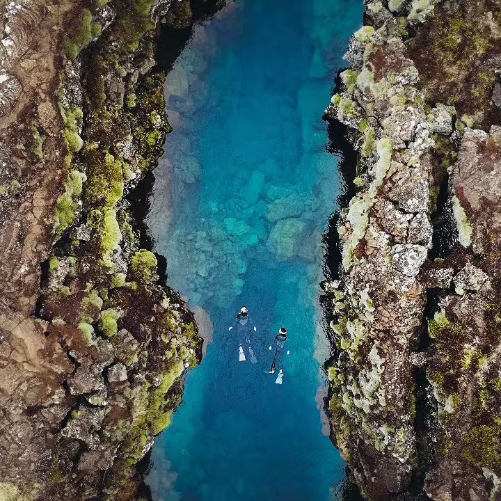 Aerial view of snorkelers exploring the crystal-clear waters between tectonic plates at Silfra in Iceland's Thingvellir National Park.
