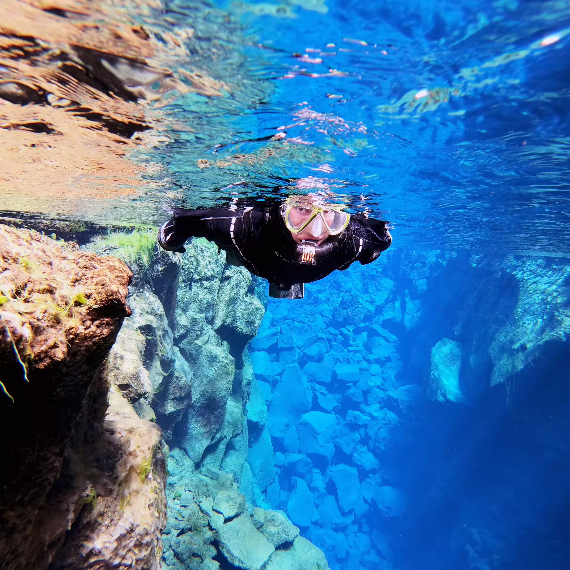 Snorkeler exploring the crystal-clear waters of Silfra Fissure in Iceland, showcasing vibrant underwater landscapes.