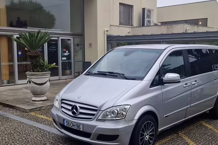 Silver Mercedes van parked outside modern building for private transfer from Porto to Santiago de Compostela.