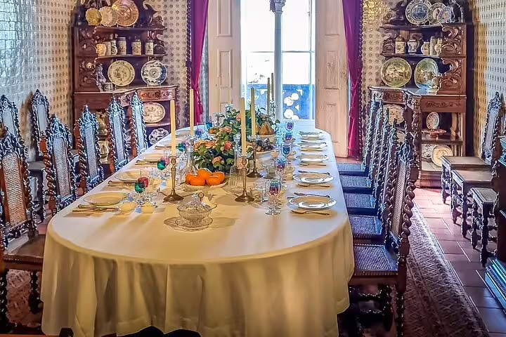 Elegant dining room in a Sintra palace showcasing ornate chairs, a lavishly set table, and intricate decor, part of a private tour from Lisbon.