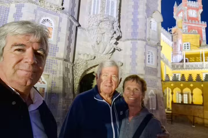 Visitors enjoying a private tour of Sintra's illuminated palaces and monuments from Lisbon, showcasing historic architecture at night.