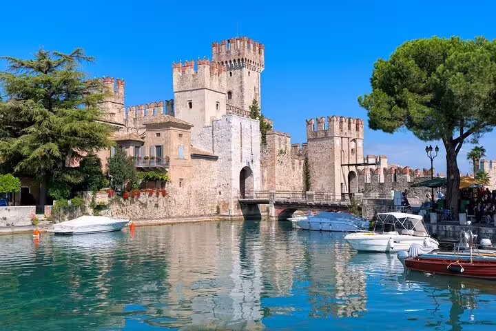 View of Sirmione Castle with boats on Lake Garda, ideal for a private Franciacorta and Sirmione tour experience.