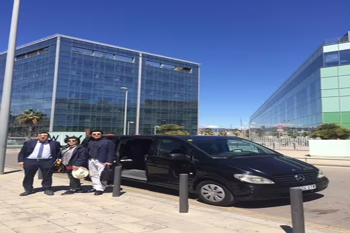 Professional tour group ready for Sitges excursion with modern transport against cityscape backdrop.