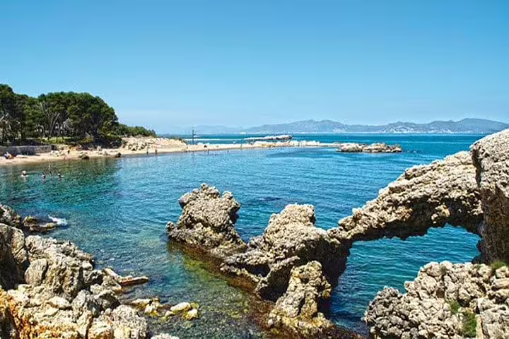 Scenic rocky coastline of Sitges with clear turquoise waters, ideal for relaxing and enjoying a beach day tour.
