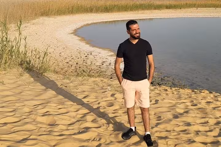 Traveler by Siwa Oasis salt lake shoreline on private 3-day Sahara safari, sandy dunes and reeds