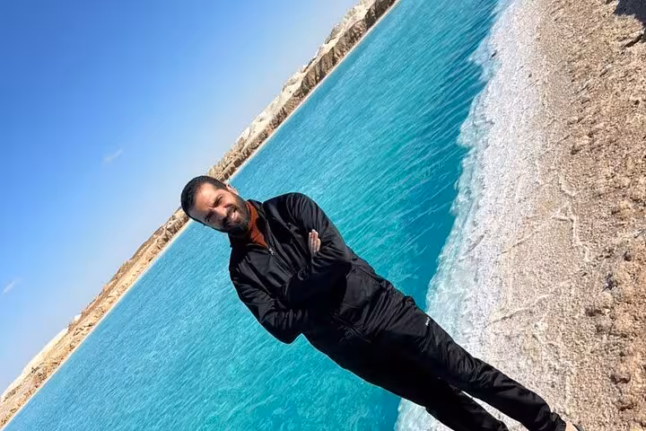 Traveler by turquoise Siwa salt lake shoreline, relaxing during a private 3-day Sahara safari with springs