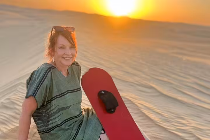 Traveler sandboarding at golden sunset in Siwa Oasis dunes on a private 3-day Sahara safari adventure
