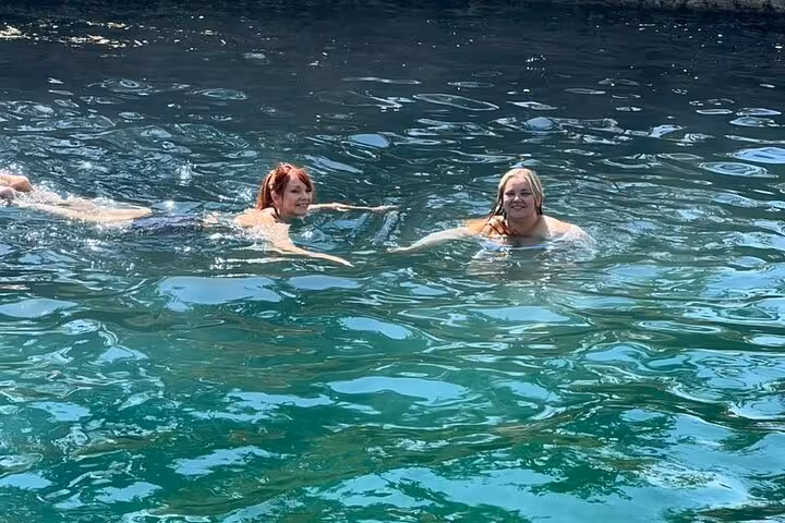 Guests swimming in a clear Siwa Oasis spring pool, relaxing break on a private 3-day Sahara safari trip