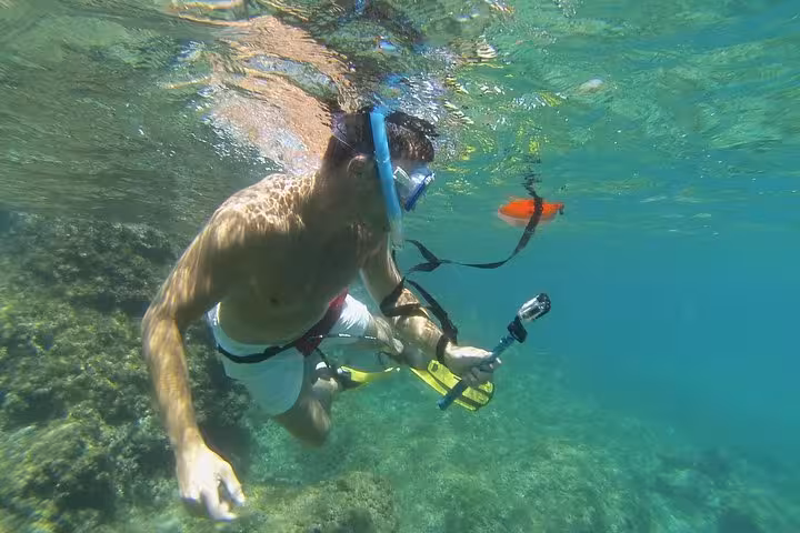 Snorkeler filming underwater in crystal-clear lagoon on Rando-Palmée island getaway tour