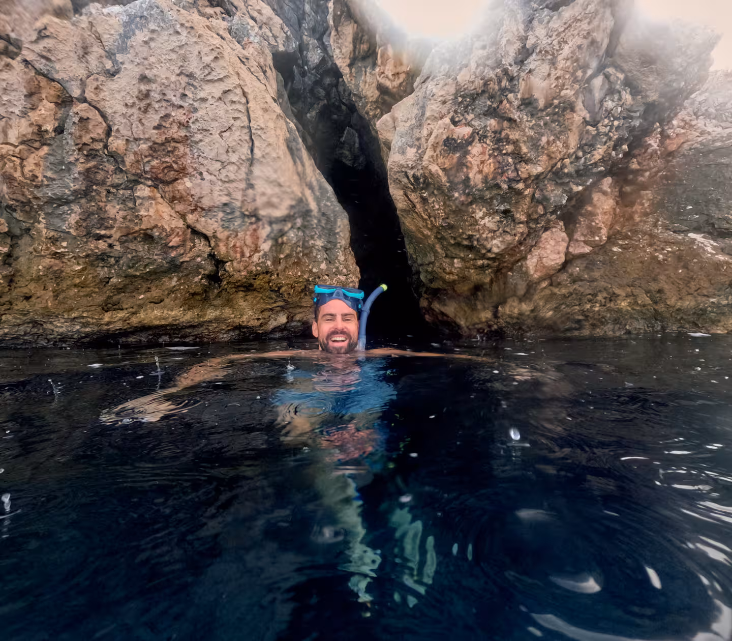 Snorkeler swimming at a hidden sea cave entrance on 3 Islands speedboat tour with cliff jumps and Blue Lagoon