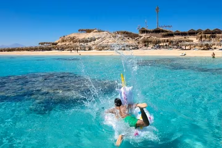 Snorkeler splashing into crystal-clear water at Mahmya Island, Hurghada private speedboat trip with lunch