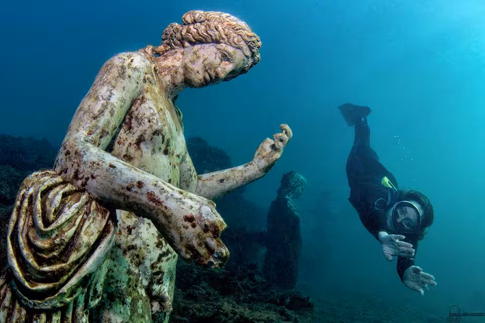 Snorkeler diving to give a closer look at one of the statues of the Ninfeo di Claudio