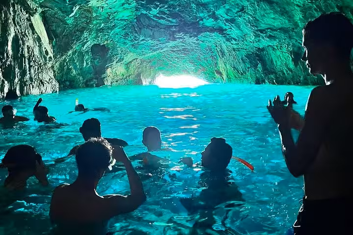 Snorkeling in a sea cave on a Calanques National Park tour from Marseille, glowing turquoise water and swimmers