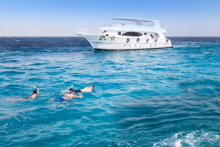 Snorkelers in turquoise Red Sea near yacht on Dolphin House snorkeling trip, Hurghada swim with dolphins