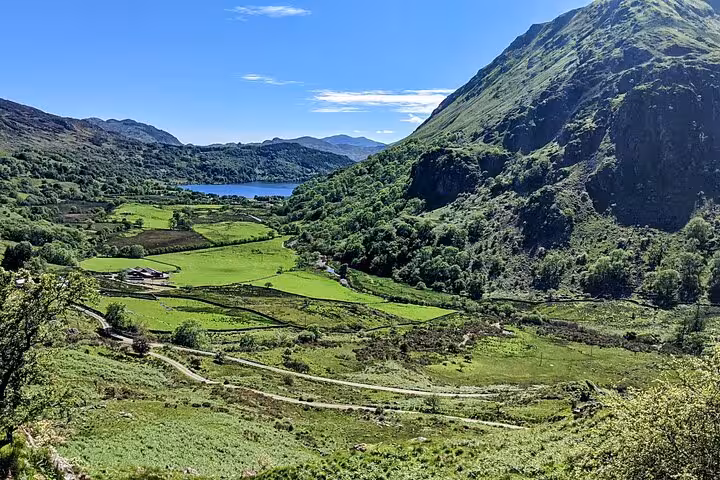 Snowdonia mountain valley with green fields and lake views, scenic landscape on Portmeirion day tour