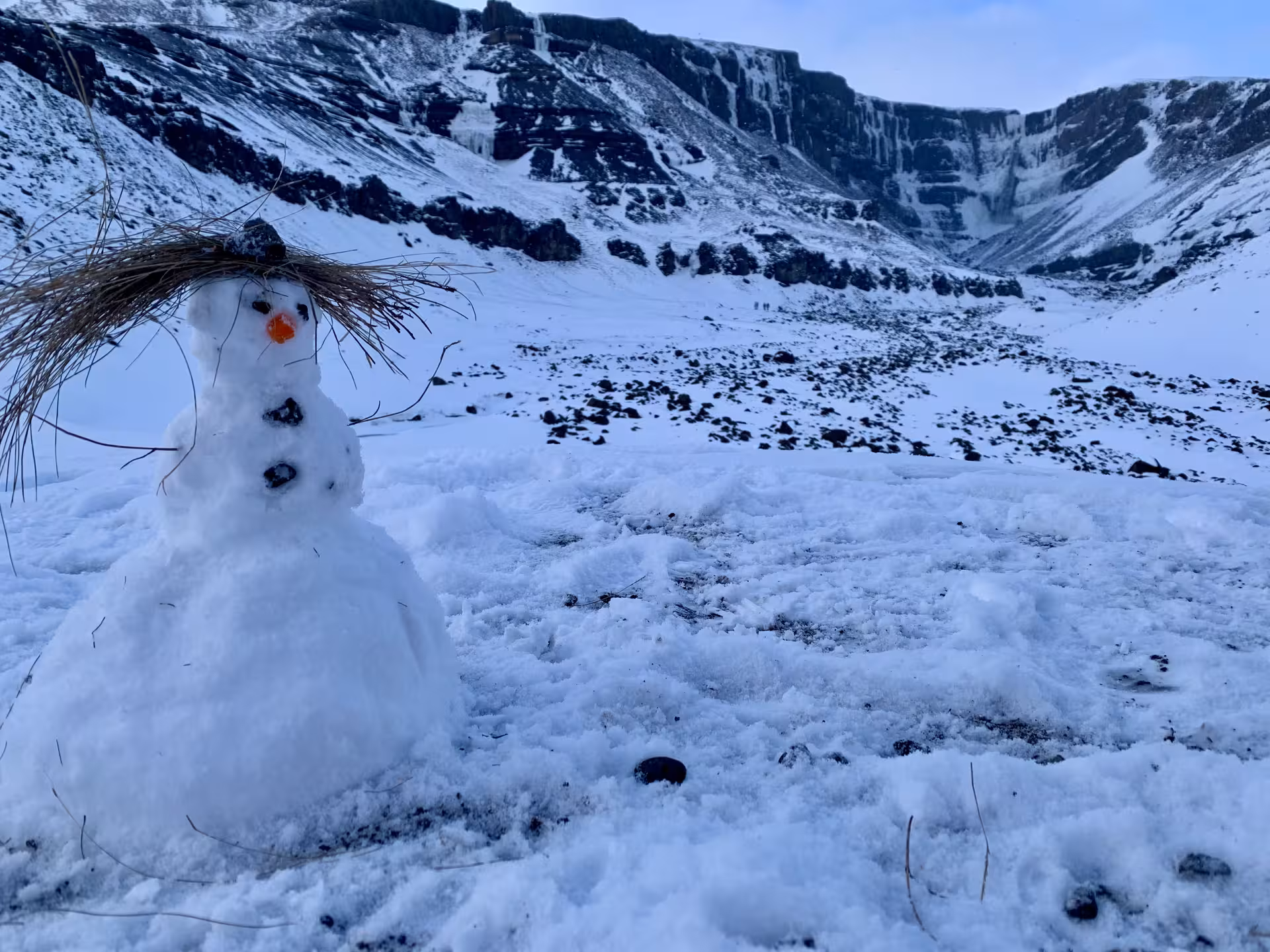 Snowman with straw hat on snowy mountainside in Iceland, perfect for women-only Viking winter adventure.